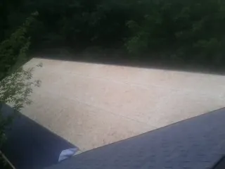 New OSB roof sheathing installed beside an existing shingle roof in Troy